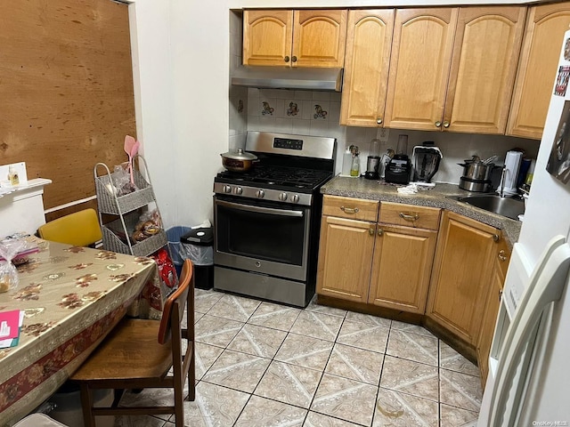 kitchen featuring decorative backsplash, gas stove, sink, light tile patterned floors, and white fridge with ice dispenser