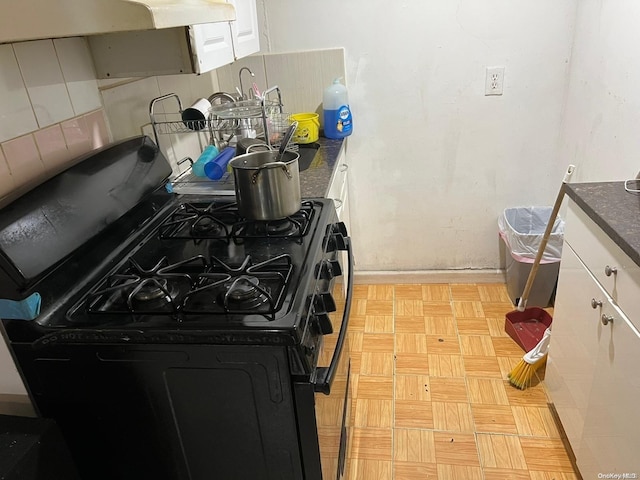 kitchen featuring gas stove, white cabinetry, and range hood