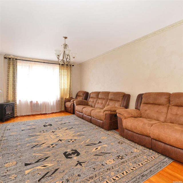 living room with wood-type flooring, a wood stove, a notable chandelier, and crown molding