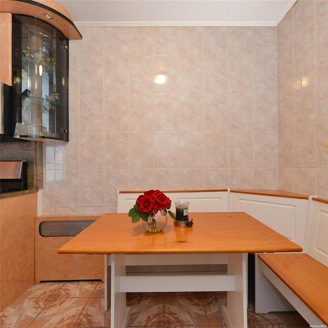 dining space featuring breakfast area, tile walls, and ornamental molding