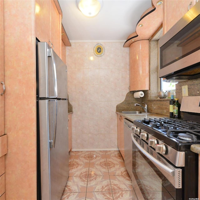 kitchen with sink, ornamental molding, tile walls, light brown cabinetry, and appliances with stainless steel finishes