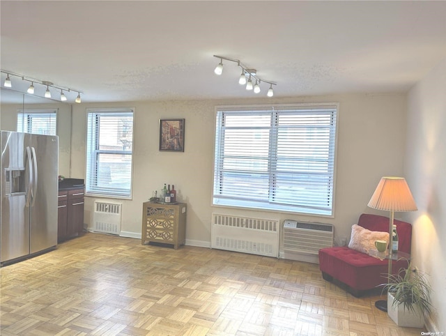 interior space with radiator, light parquet flooring, a wall mounted AC, and track lighting