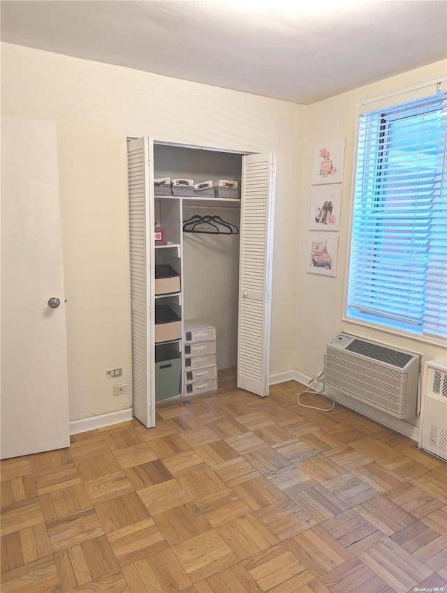 unfurnished bedroom with light parquet floors and a wall mounted AC