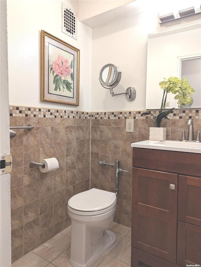 bathroom with tile patterned floors, vanity, tile walls, and toilet