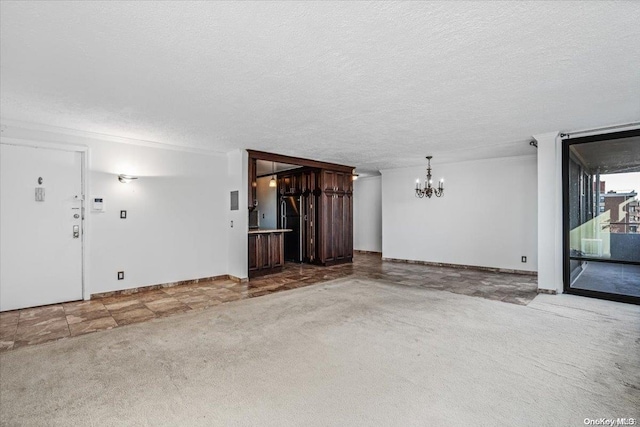 spare room with carpet flooring, a textured ceiling, and a chandelier