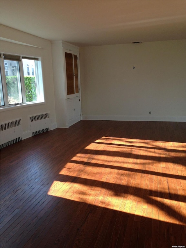 unfurnished room featuring radiator and hardwood / wood-style floors