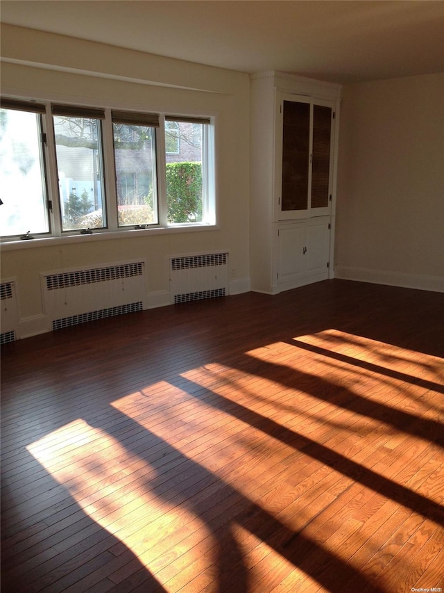 empty room featuring hardwood / wood-style floors and radiator heating unit