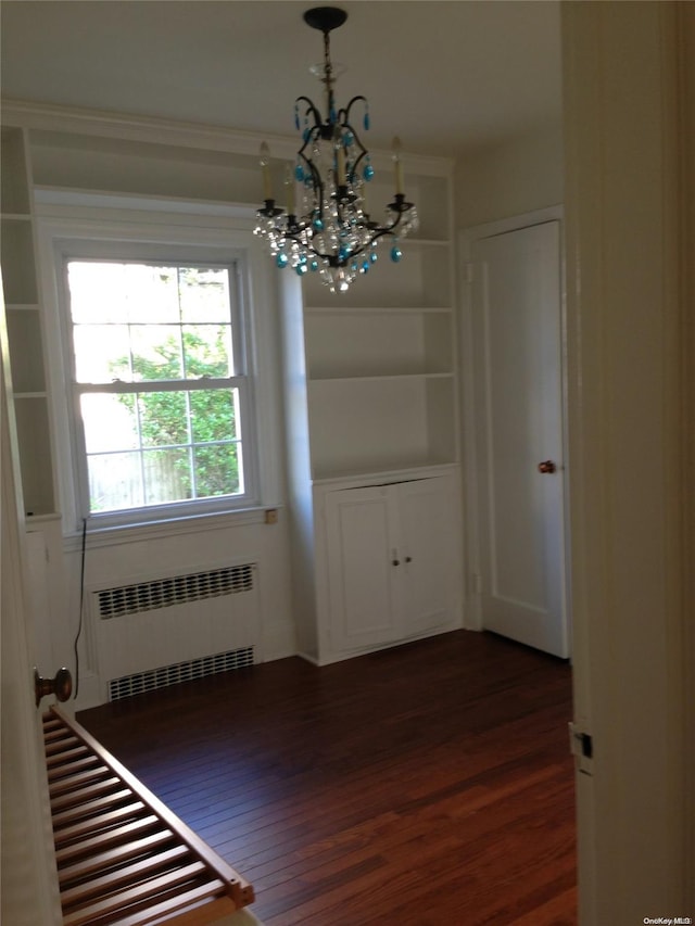 unfurnished dining area featuring radiator heating unit, dark hardwood / wood-style floors, and a notable chandelier