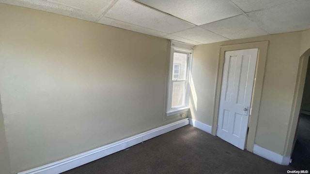 unfurnished bedroom with a paneled ceiling and a baseboard heating unit