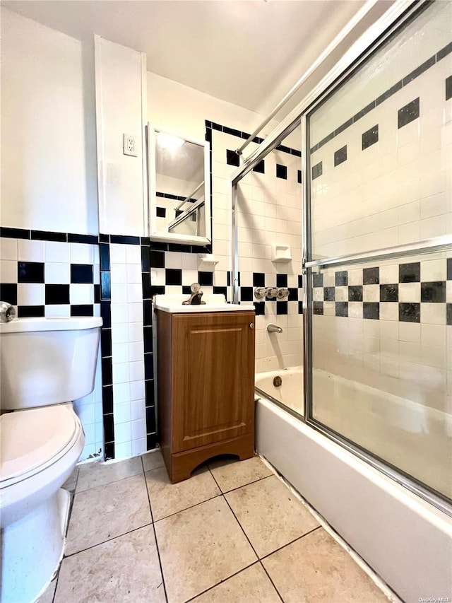 full bathroom featuring vanity, combined bath / shower with glass door, tile patterned flooring, toilet, and tile walls