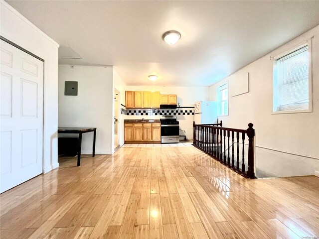 kitchen featuring decorative backsplash, stainless steel range, exhaust hood, white refrigerator, and light hardwood / wood-style floors