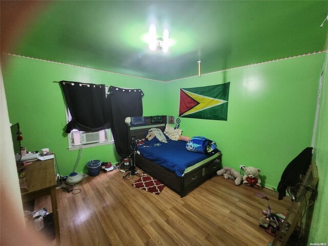 bedroom with cooling unit and wood-type flooring