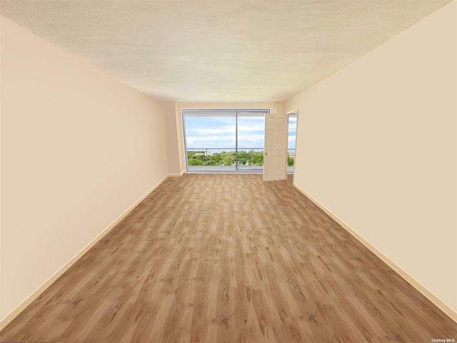 spare room featuring a textured ceiling and light hardwood / wood-style flooring