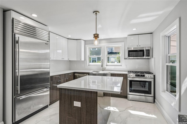 kitchen with appliances with stainless steel finishes, dark brown cabinets, sink, white cabinets, and a kitchen island