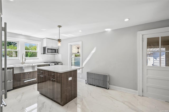 kitchen featuring sink, a center island, radiator heating unit, decorative light fixtures, and appliances with stainless steel finishes