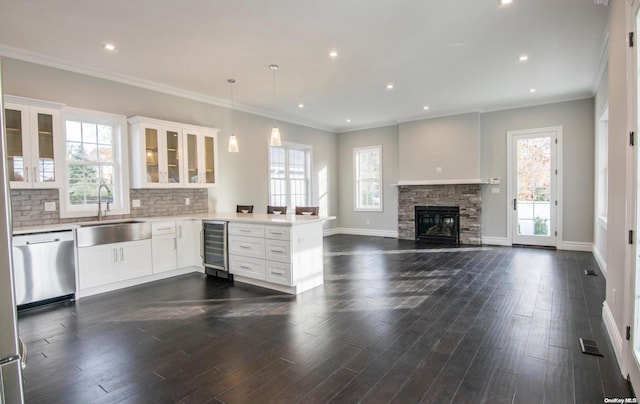 kitchen featuring kitchen peninsula, stainless steel dishwasher, plenty of natural light, and beverage cooler