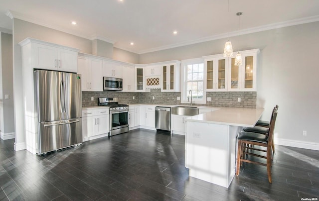 kitchen with ornamental molding, stainless steel appliances, decorative light fixtures, dark hardwood / wood-style floors, and white cabinetry