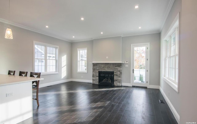 unfurnished living room featuring dark hardwood / wood-style flooring, a stone fireplace, and crown molding