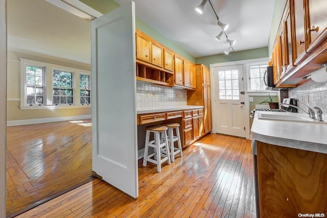 kitchen with rail lighting, a kitchen bar, light wood-type flooring, and backsplash