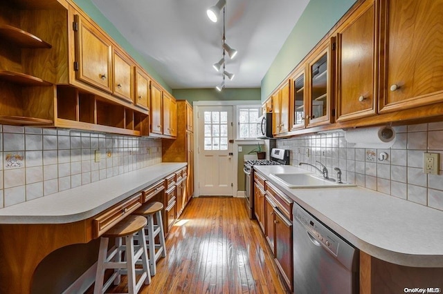 kitchen featuring sink, backsplash, light hardwood / wood-style floors, a breakfast bar, and appliances with stainless steel finishes