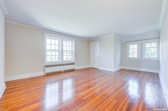 spare room featuring ornamental molding, radiator, and light hardwood / wood-style flooring