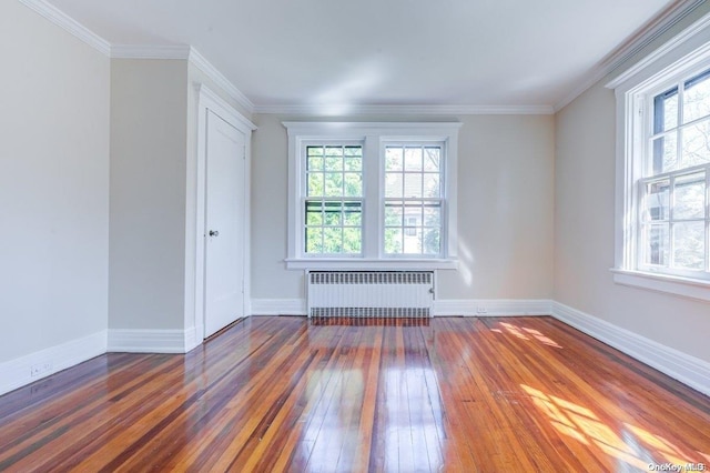 empty room featuring dark hardwood / wood-style floors, radiator heating unit, and crown molding