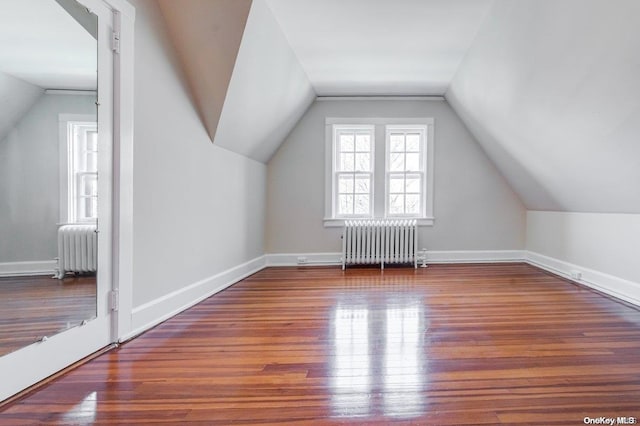 additional living space with radiator heating unit, vaulted ceiling, and wood-type flooring