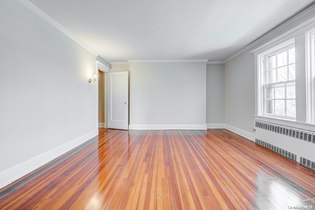 empty room featuring hardwood / wood-style floors, radiator, and ornamental molding