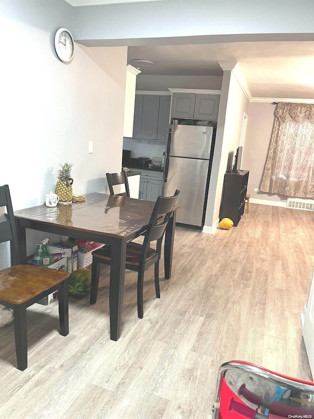 dining space featuring ornamental molding and light wood-type flooring