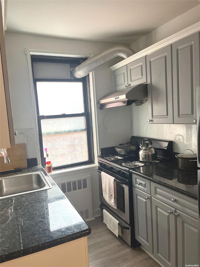 kitchen featuring gray cabinets, radiator heating unit, sink, and stainless steel gas range