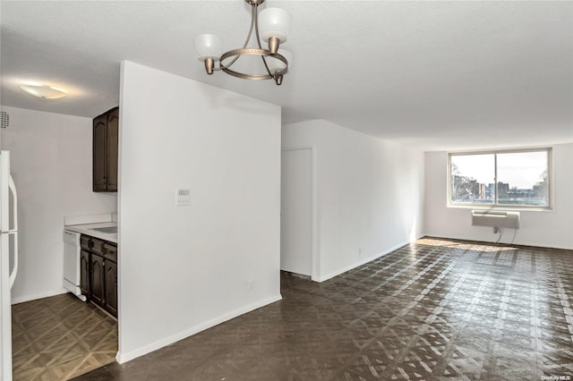 interior space featuring a notable chandelier, white dishwasher, an AC wall unit, a textured ceiling, and dark brown cabinets