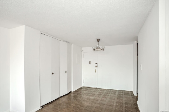 interior space with a textured ceiling and a chandelier