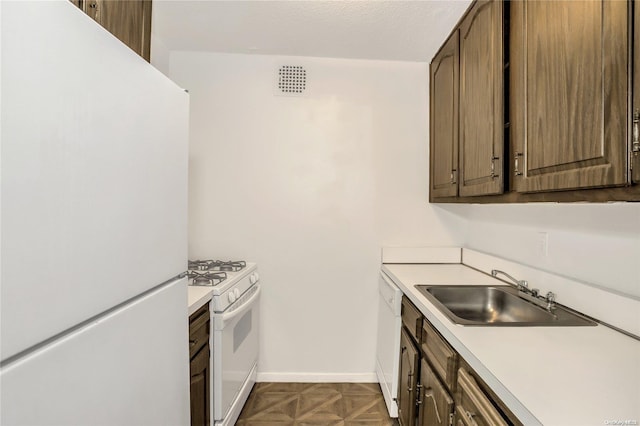 kitchen featuring dark parquet flooring, white appliances, a textured ceiling, and sink