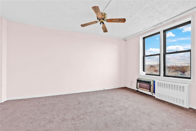 empty room with carpet, a textured ceiling, radiator, and ceiling fan