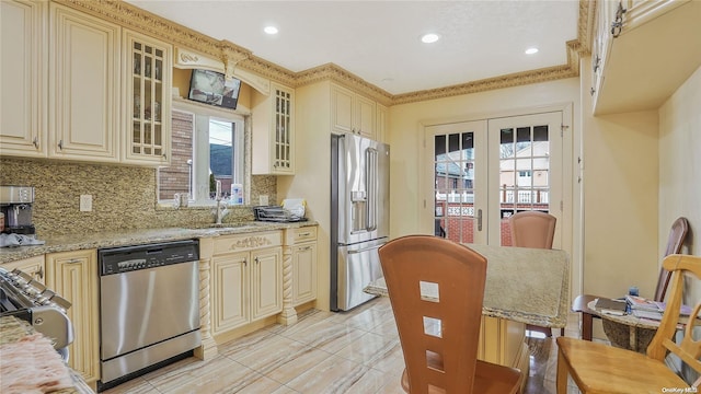 kitchen featuring cream cabinets, sink, tasteful backsplash, light stone counters, and stainless steel appliances