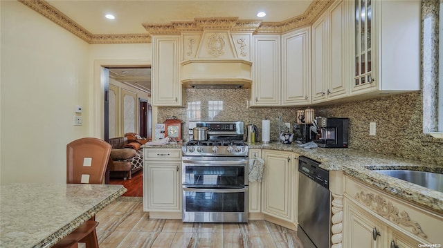 kitchen featuring light stone counters, ornamental molding, stainless steel appliances, and cream cabinets