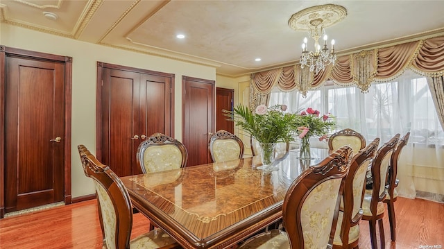 dining area with light wood-type flooring, crown molding, and a chandelier