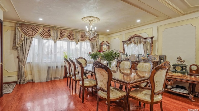 dining space featuring wood-type flooring, crown molding, and a notable chandelier