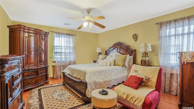 bedroom with multiple windows, ceiling fan, and light wood-type flooring