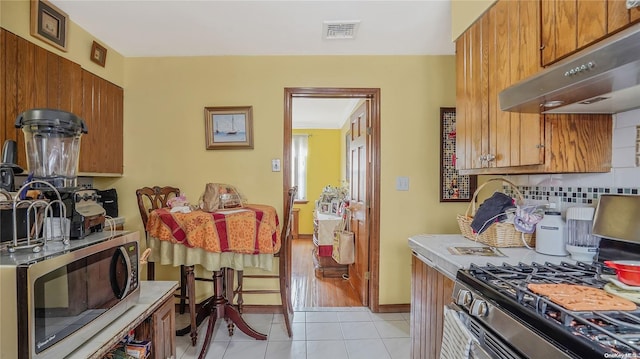 kitchen featuring decorative backsplash, light tile patterned flooring, and stainless steel appliances