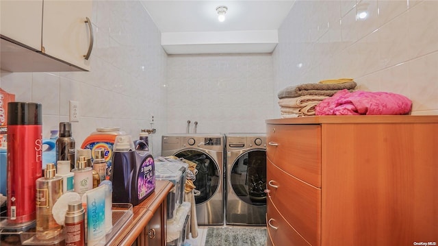 laundry area with independent washer and dryer and tile walls