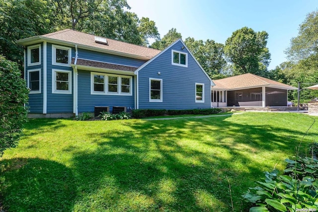 back of property with a yard and a sunroom