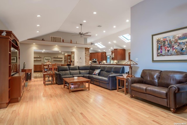 living room featuring a skylight, ceiling fan, high vaulted ceiling, and light hardwood / wood-style floors