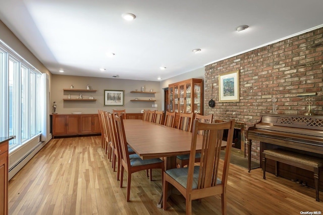 dining space featuring a baseboard radiator, light hardwood / wood-style flooring, and brick wall