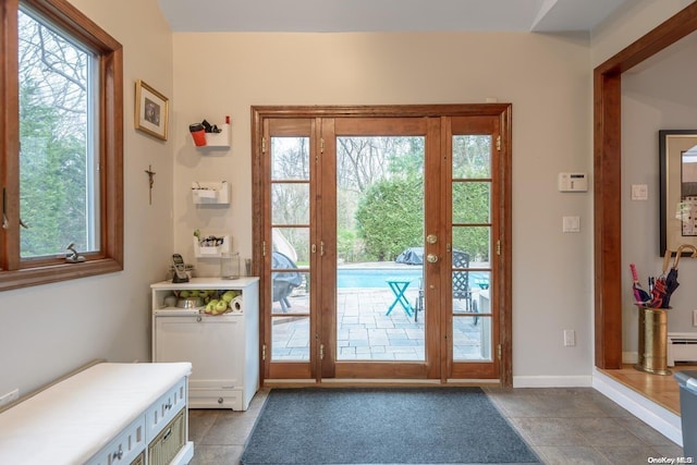 doorway featuring french doors, a baseboard heating unit, a healthy amount of sunlight, and light tile patterned flooring