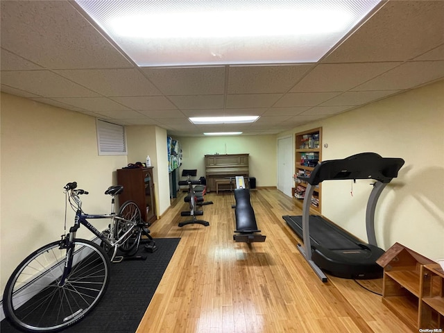 workout room with a paneled ceiling and wood-type flooring