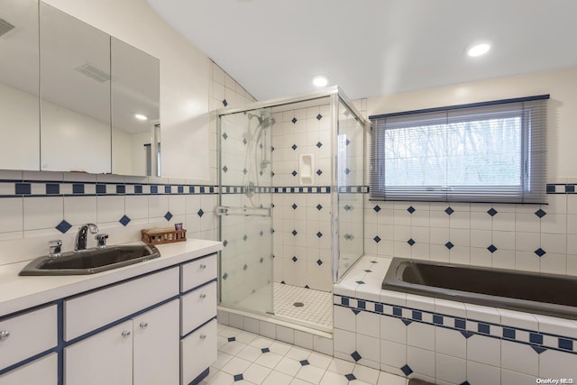 bathroom featuring separate shower and tub, tile patterned floors, vanity, and tile walls