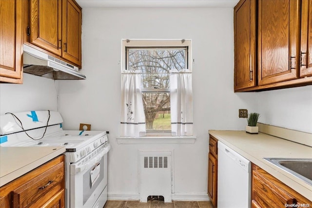 kitchen featuring radiator, sink, light tile patterned floors, and white appliances