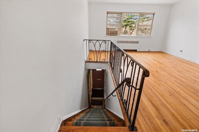 staircase with cooling unit, wood-type flooring, and radiator