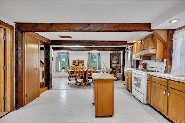 kitchen with custom range hood, a kitchen island, white gas range, and beam ceiling